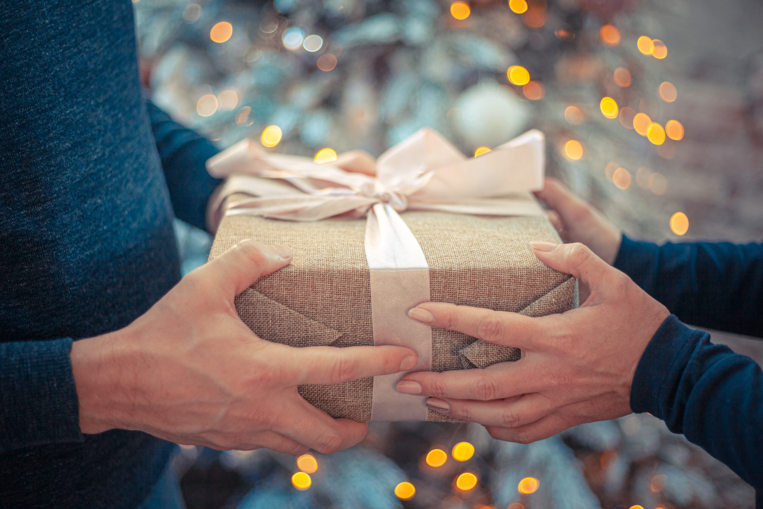 une personne tend un cadeaux de noël à une autre personne.